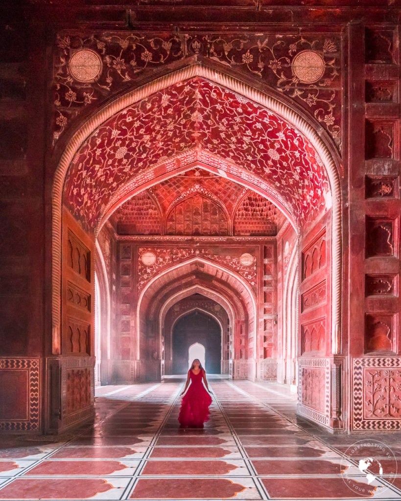 A girl in red admiring the beautiful intricate details of the mosque at Taj Mahal