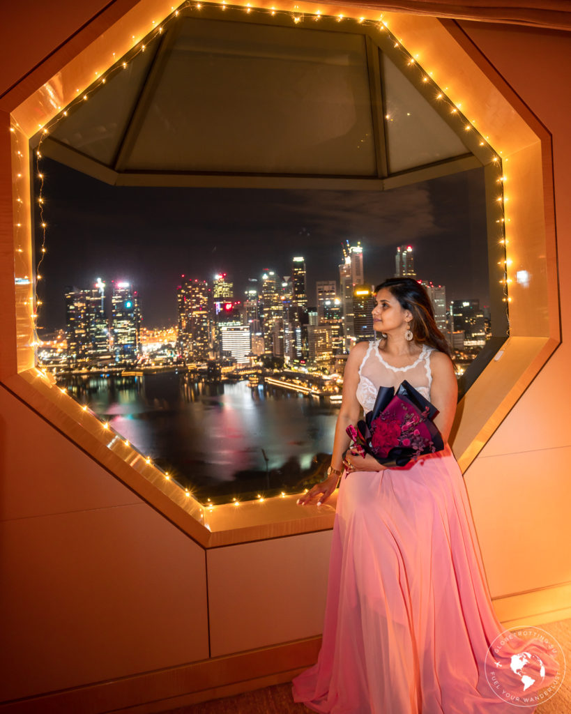 A girl holding bouquet and admiring the night views of Singapore skyline from her bedroom window view