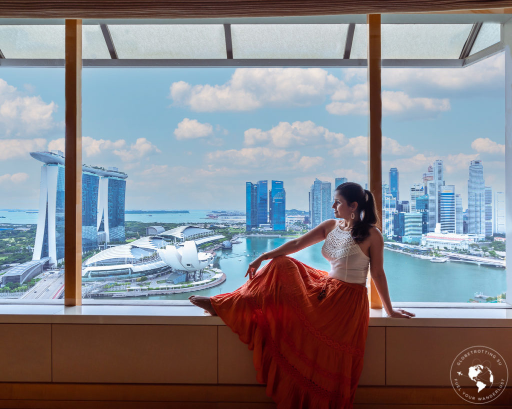 Girl sitting and enjoying the vast expanse of Singapore skyline view from her living room at Ritz Carlton Millenia, Singapore