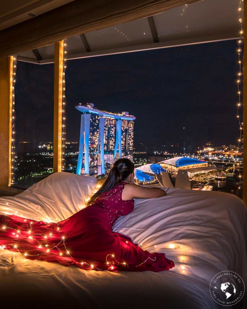 A girl dreaming seeing the Singapore skyline view at night from One-bedroom Millenia Suite at Ritz Carlton