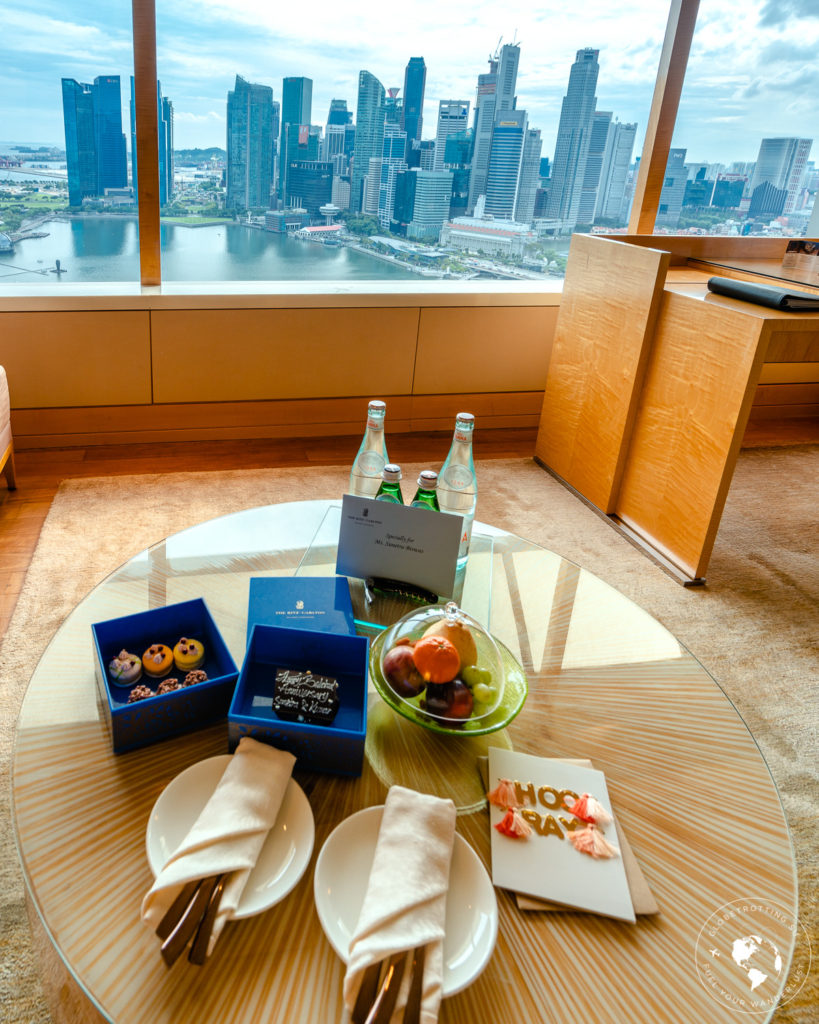 Sweets, cakes, fruits, personalized card as welcome treats in room overlooking Singapore skyline